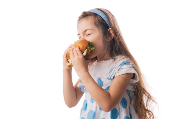 Image of a little girl biting into a burger. All the places kids eat free or for £1 during May half term