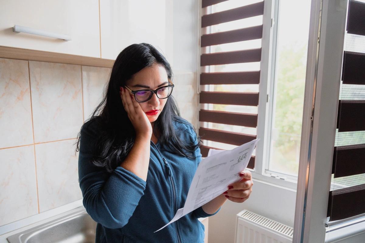 A stock image of a worried woman looking at an energy bill.