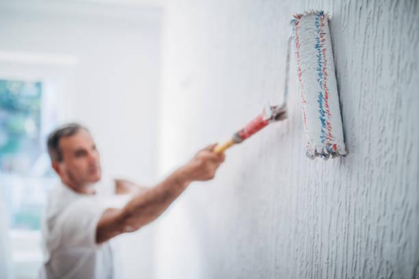 Image of a man painting a wall. DIY on a budget. Do up your home for less
