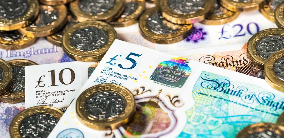 A pile of UK £20, £10 and £5 banknotes with £1 coins.