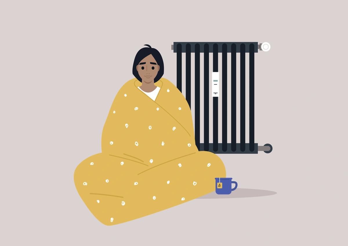 An illustration of a young man wrapped in a yellow duvet sat by a radiator with a cup of tea.