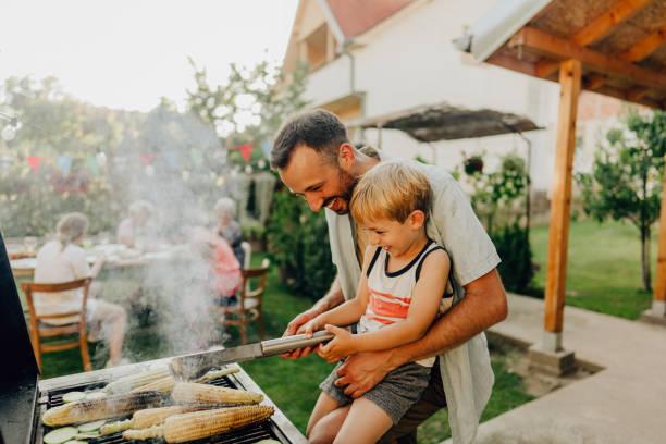 Image of a man with his son cooking on a BBQ. Aldi cuts food prices ahead of Father's Day