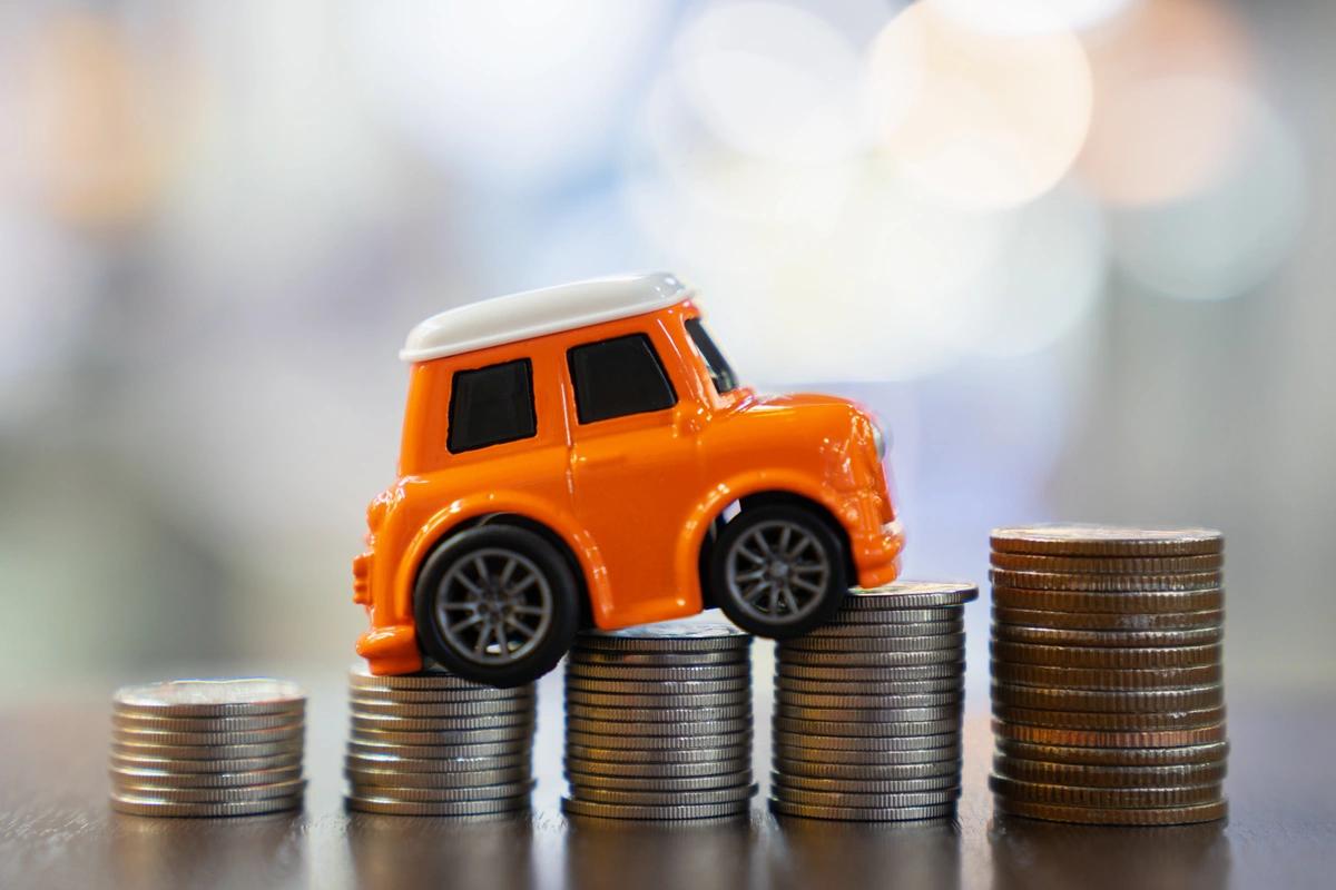 Orange toy car on a pile of coins