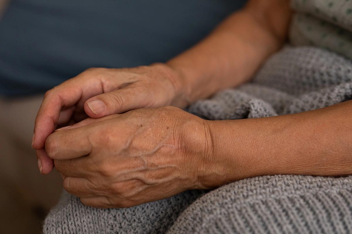 An old person's hands on a blanket.