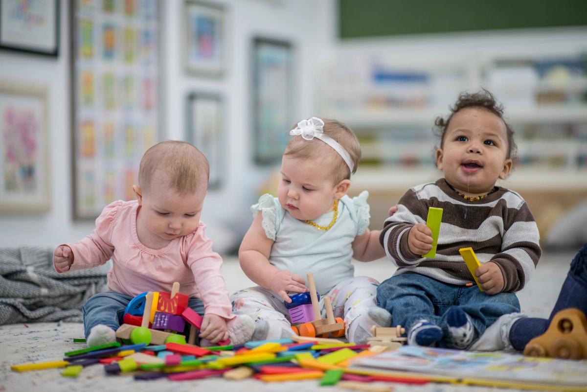 A stock image of young children of different ethnicities sat playing with toys in a childcare setting.