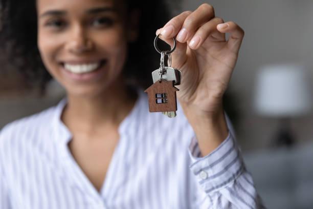 image of a woman in the background holding a set of house keys in the foreground