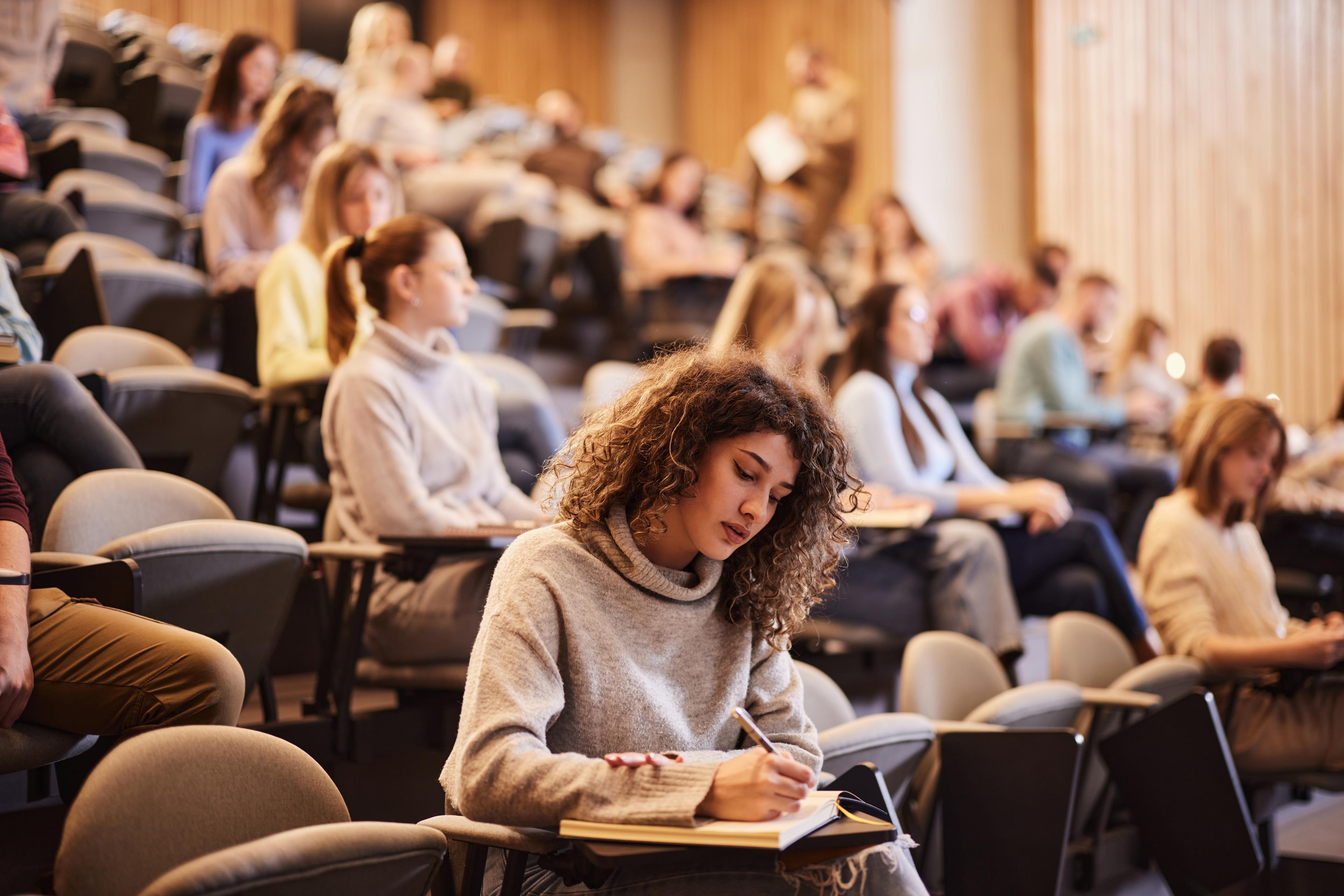 University students taking notes in a lecture hall.