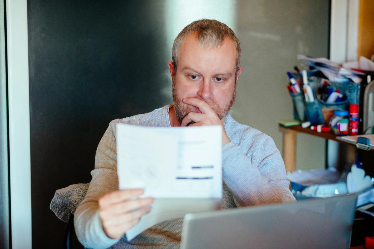 A man looks at his energy bill with a worried expression.